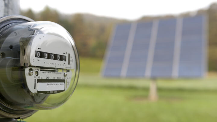 Electricity meter with solar PV panels in background.