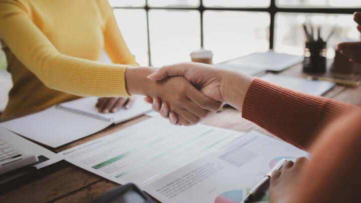 Two people shaking hands over a contract.